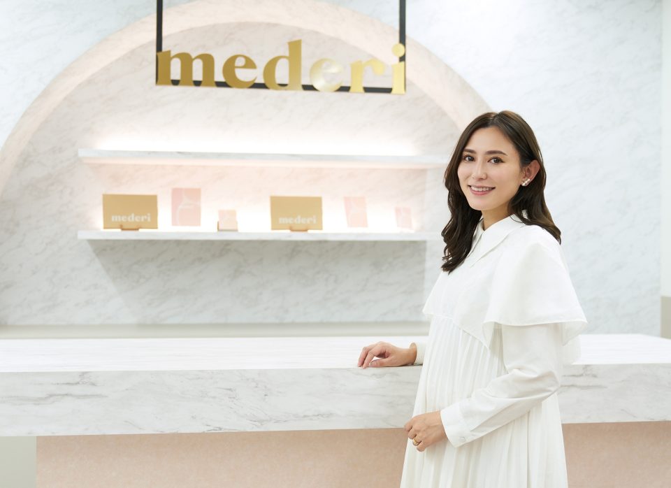 mederi株式会社のロゴと坂梨亜里咲さん。奥のあるのはオンラインでメデリピルのサービスを申し込んだときに配送されるもの。